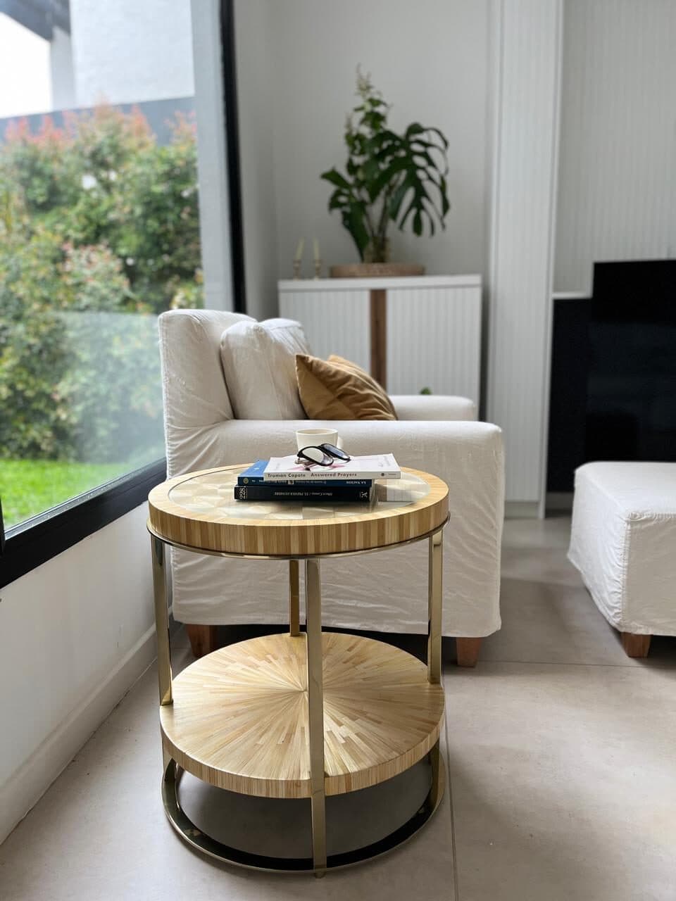 Mesa auxiliar radial junto a un sillón blanco